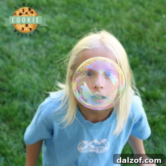 A child, H, enjoying bubble fun during summer, with a perfect bubble-face picture.