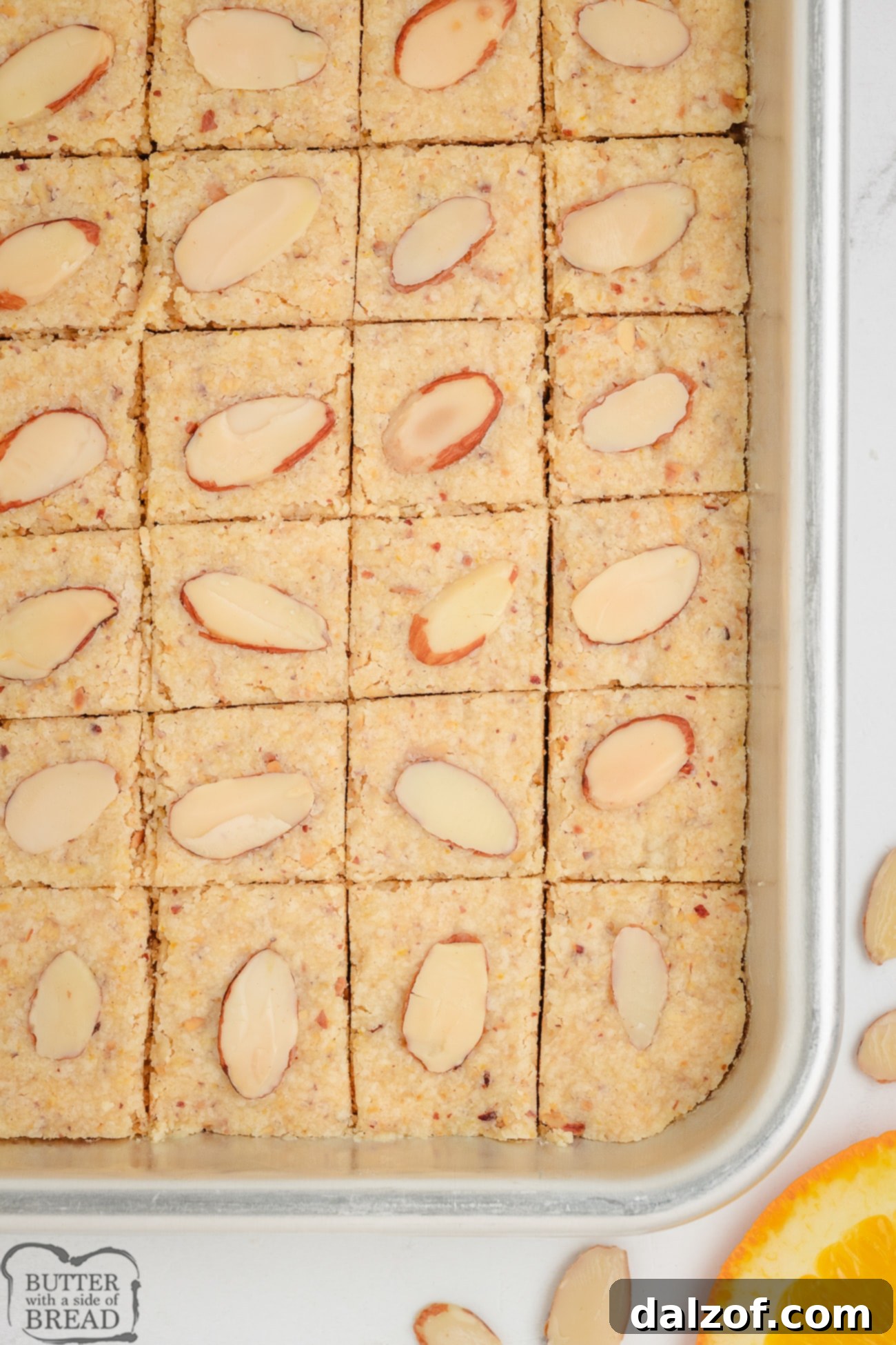 A close-up view of golden-brown almond citrus shortbread baking in a rectangular pan, ready to be cut.