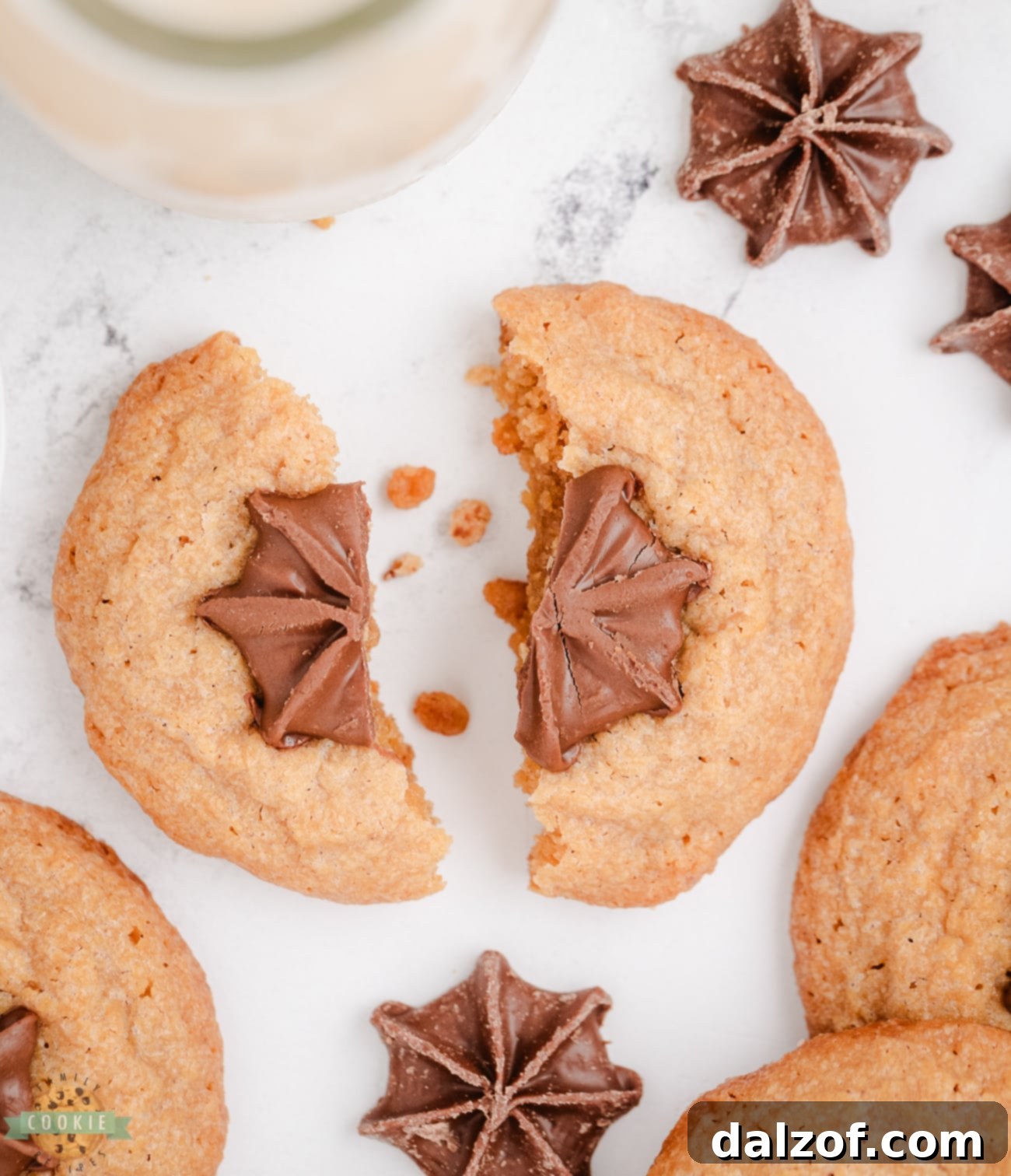 Peanut butter kiss cookie broken in half, revealing its soft, chewy interior and molten chocolate center.