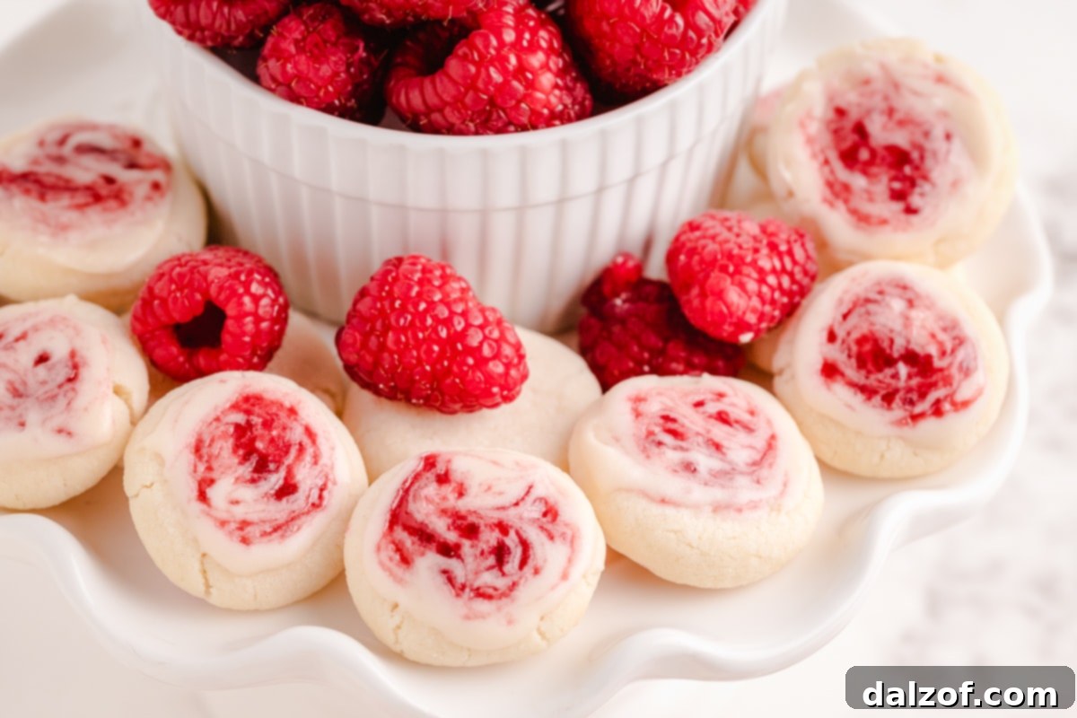 Close-up of freshly baked Raspberry Meltaway Cookies with almond glaze and raspberry jam swirl