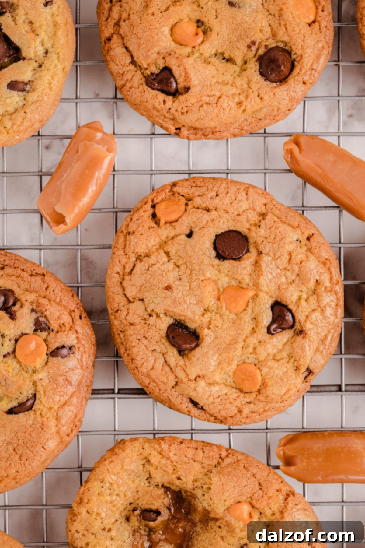 A plate of warm Caramel Chocolate Chip Cookies, with one broken open to show the melted caramel inside