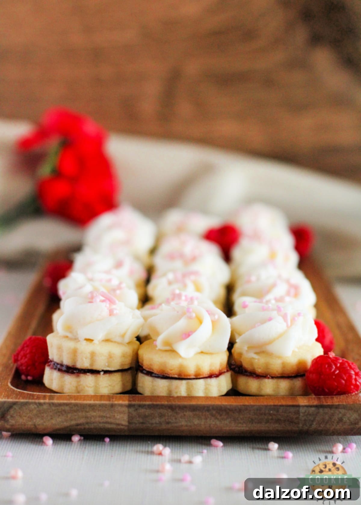 Shortbread cookie sandwiches filled with raspberry jam and topped with buttercream frosting. 