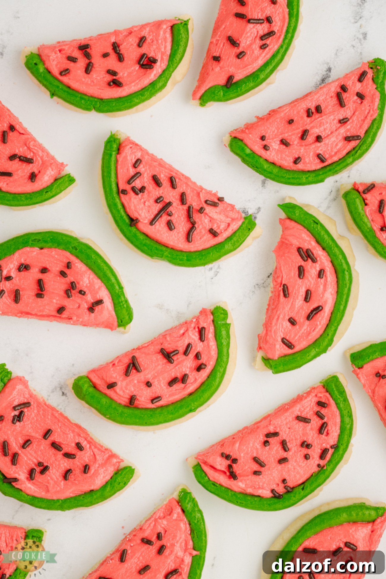 Close-up of perfectly frosted half-circle watermelon slice cookies on a cooling rack.
