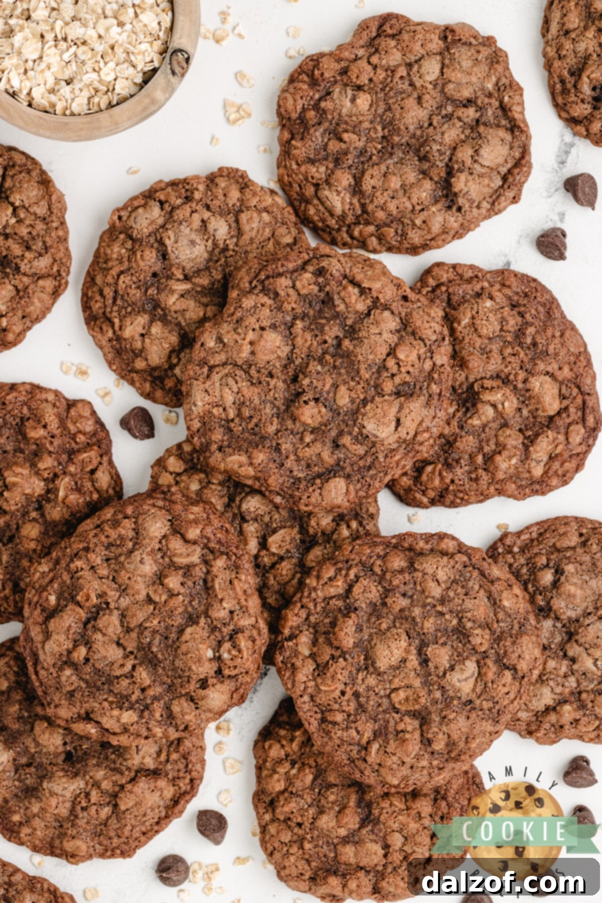Batch of freshly baked chocolate cookies with visible oats and melted chocolate chips on a cooling rack.