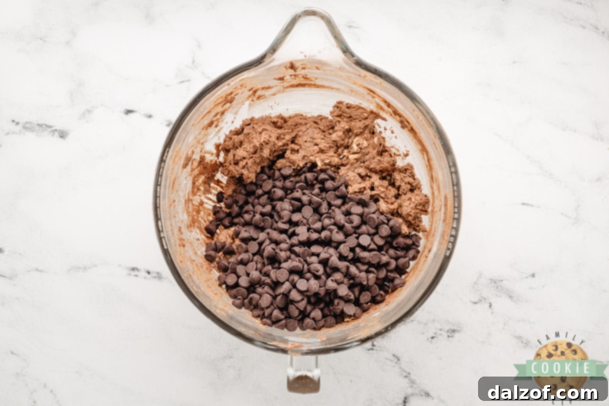Electric mixer blending butter and sugars in a large mixing bowl, a key step for double chocolate oatmeal cookie dough.