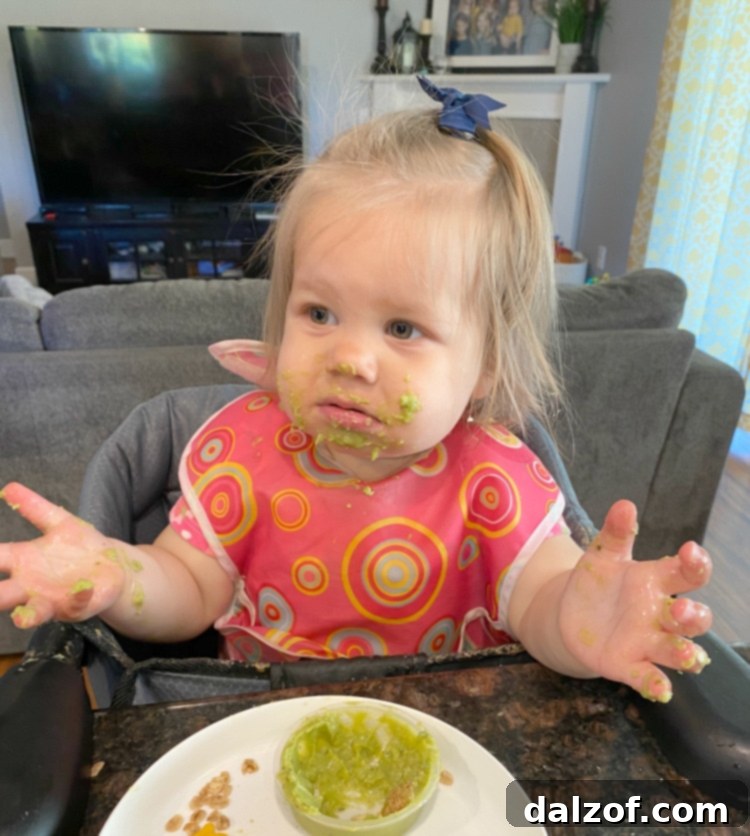 A cute 18-month-old child enjoying guacamole, with a joyful and slightly messy expression.