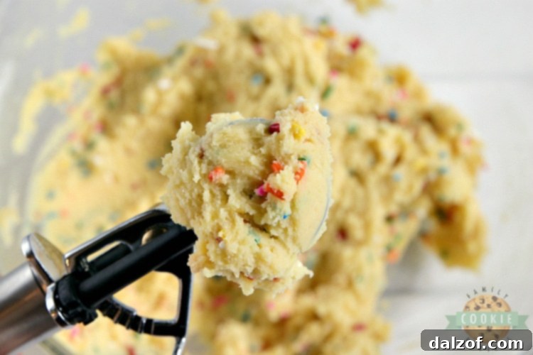 A scoop of vanilla cookie dough generously mixed with colorful sprinkles, ready for baking.