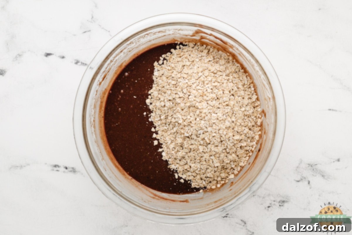 Incorporating quick oats into the rich chocolate peanut butter cookie mixture, the final step before shaping the no-bake cookies.
