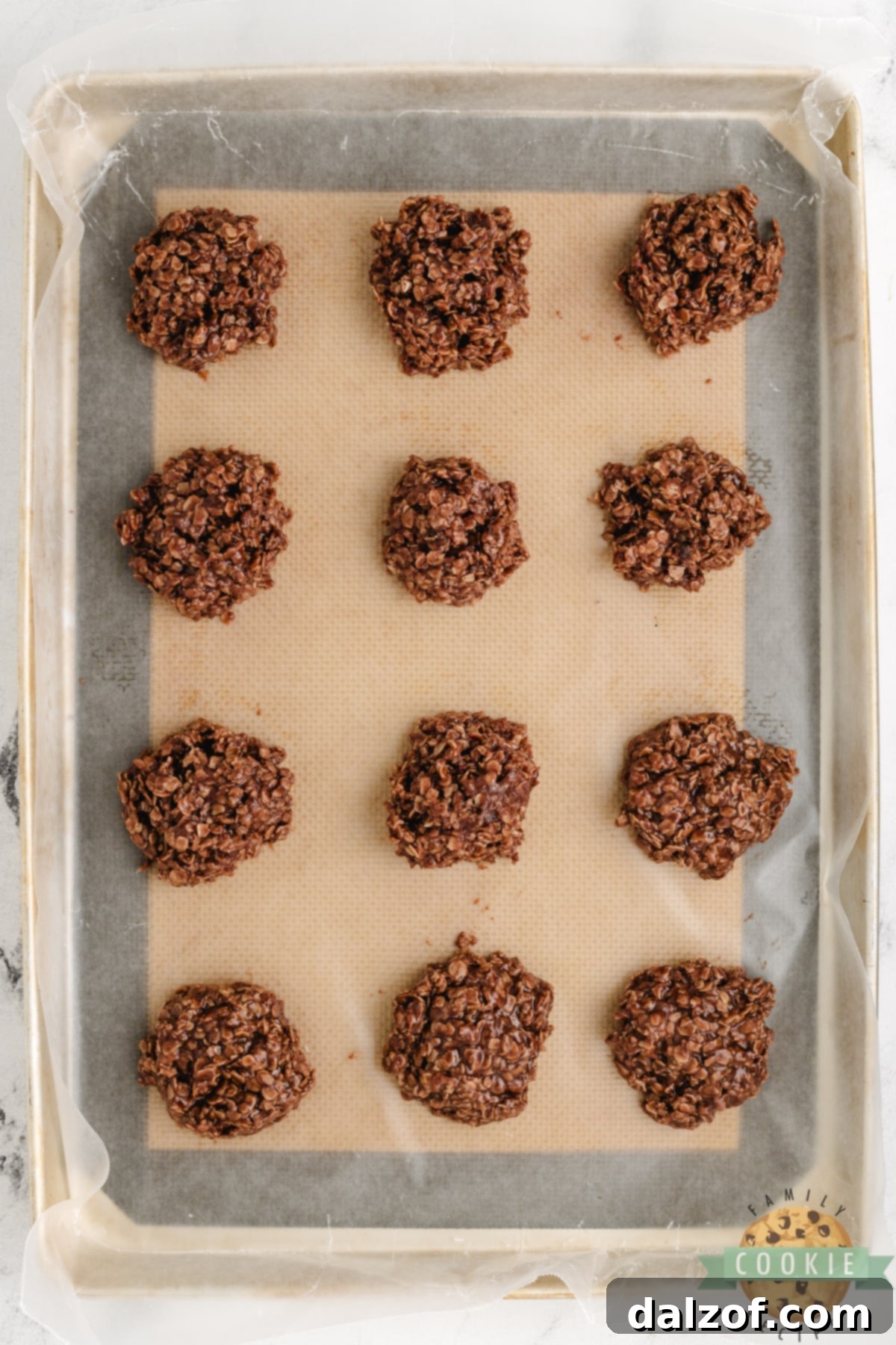 Freshly scooped no-bake cookies neatly dropped by spoonfuls onto wax paper on a cookie sheet, ready for refrigeration to set.