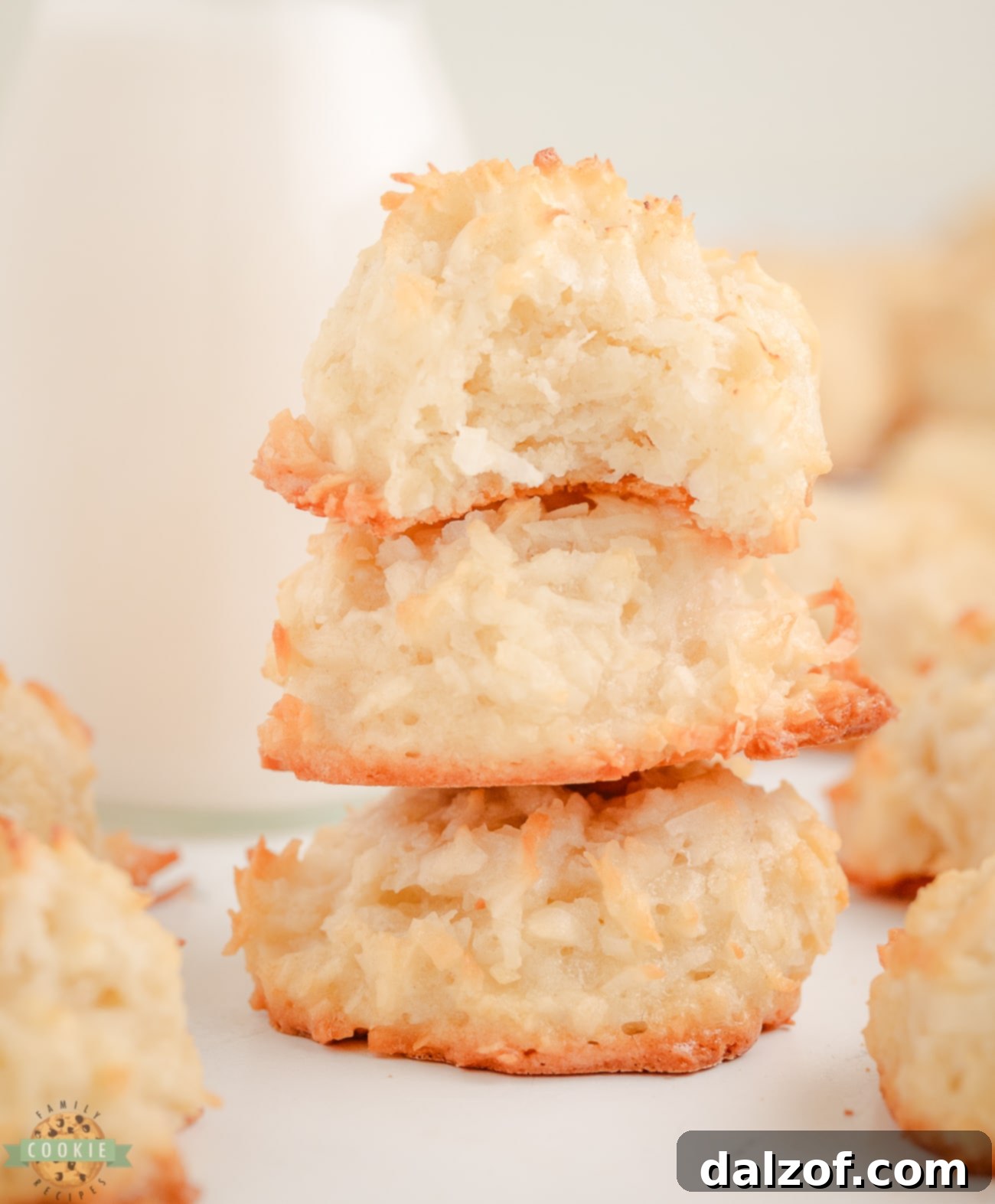 A stack of golden coconut macaroons with one showing a delightful bite taken out, revealing its moist, chewy interior.