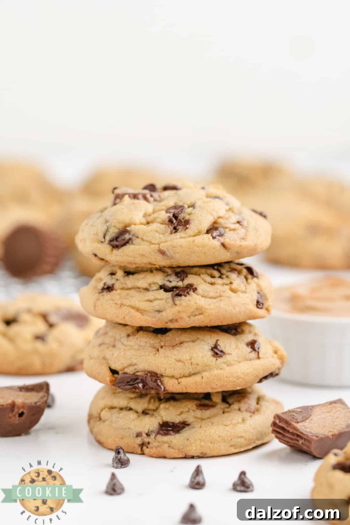 Ultimate Reese Peanut Butter Pudding Cookies 3 Peanut butter cookies made with vanilla pudding mix and Reese's peanut butter cups. The image displays freshly baked cookies cooling on a wire rack, glistening with melted chocolate and peanut butter cup pieces.