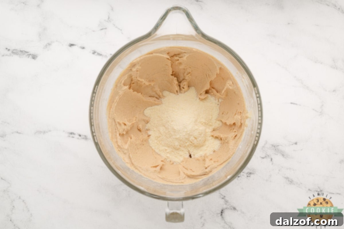 Ultimate Reese Peanut Butter Pudding Cookies 9 Add vanilla pudding mix to peanut butter cookie dough. A packet of instant vanilla pudding mix being poured into the mixing bowl with the wet cookie dough ingredients.