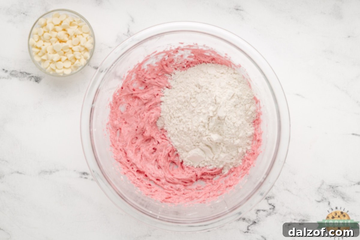 Adding the pre-mixed flour to the wet raspberry-infused cookie dough ingredients.