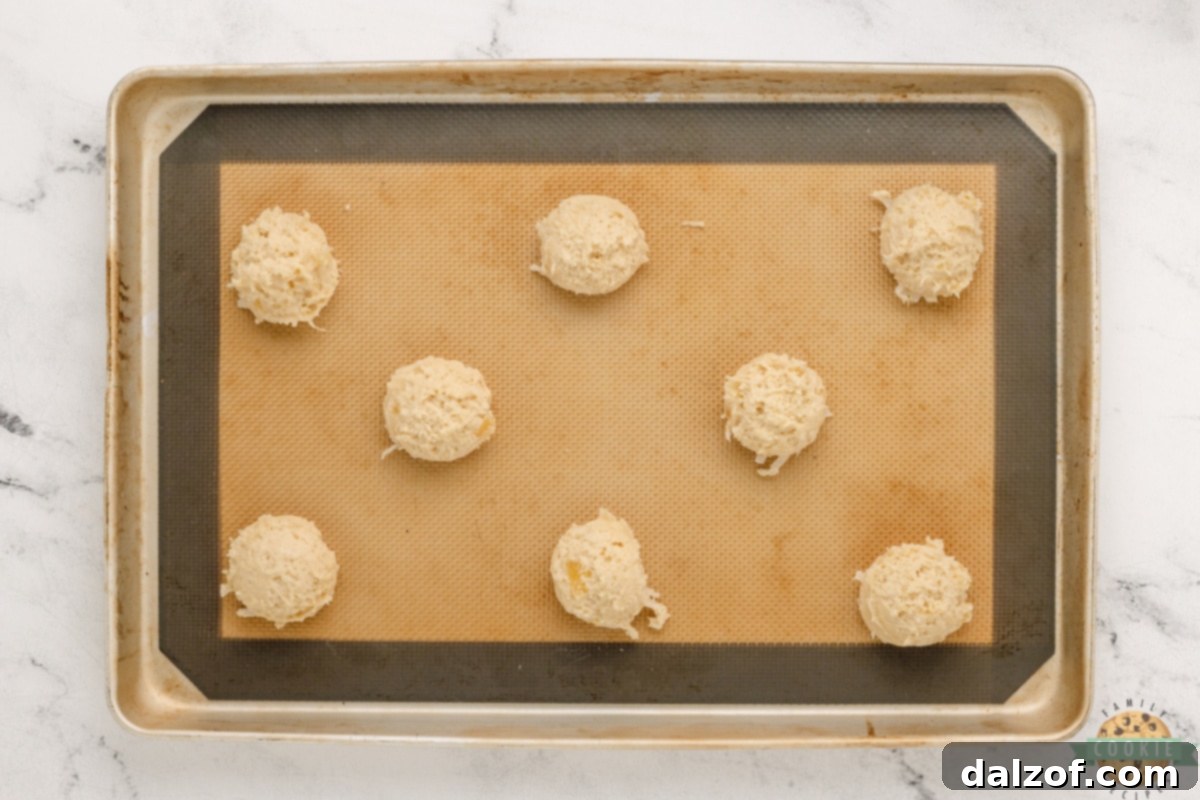 Scooping pina colada cookies onto cookie sheet. 