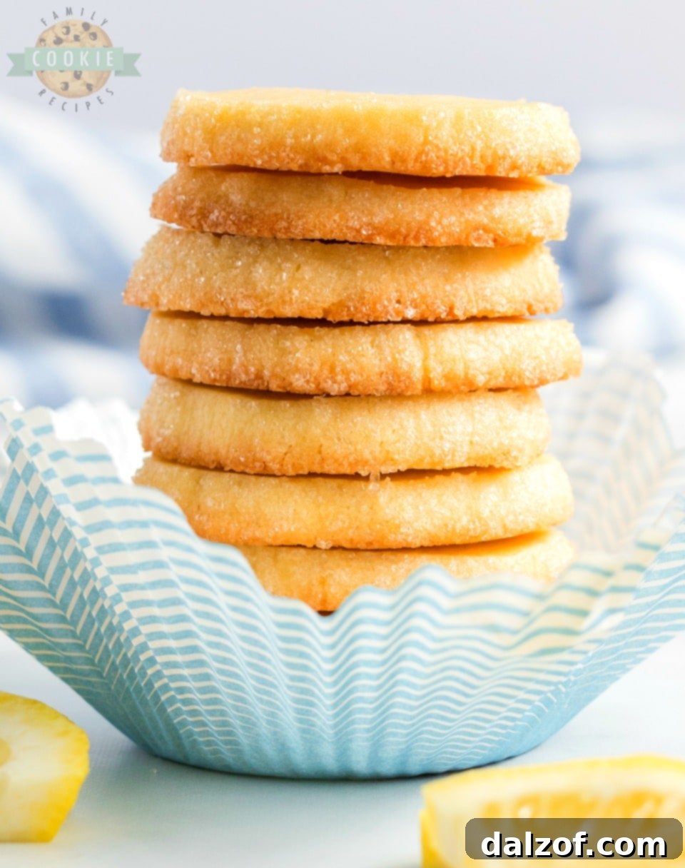 A large stack of Lemon Slice and Bake Shortbread cookies, artfully arranged to highlight their vibrant zest and sugary coating.