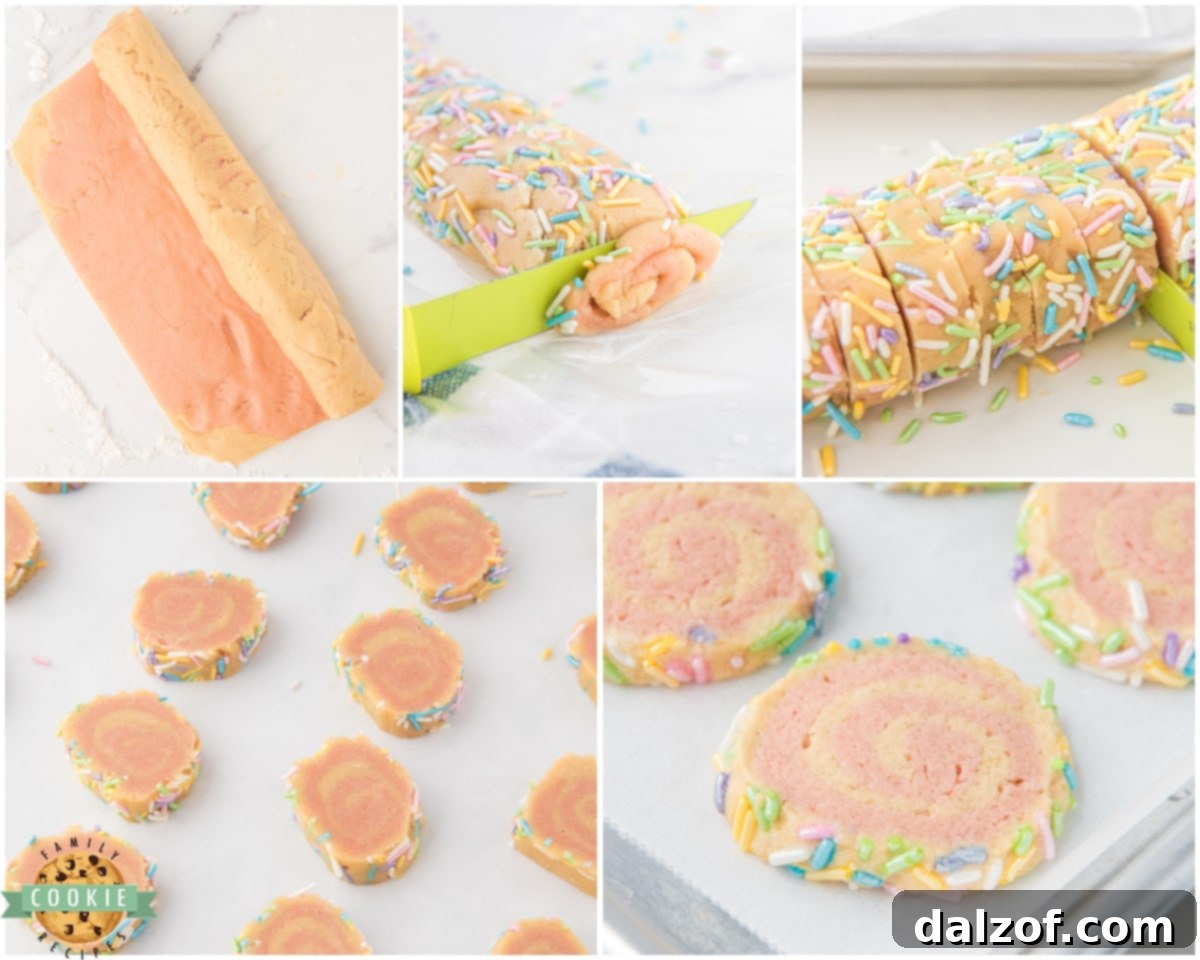 A log of pink and white pinwheel cookie dough, rolled and ready to be coated in sprinkles, resting on plastic wrap on a countertop.