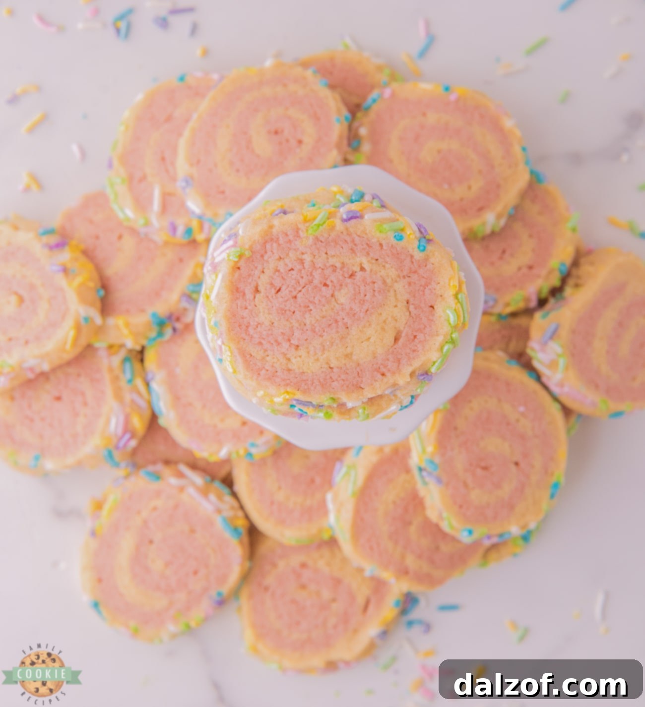 A vibrant pile of pink and white pinwheel cookies, adorned with pastel sprinkles, showcasing their beautiful swirled pattern.
