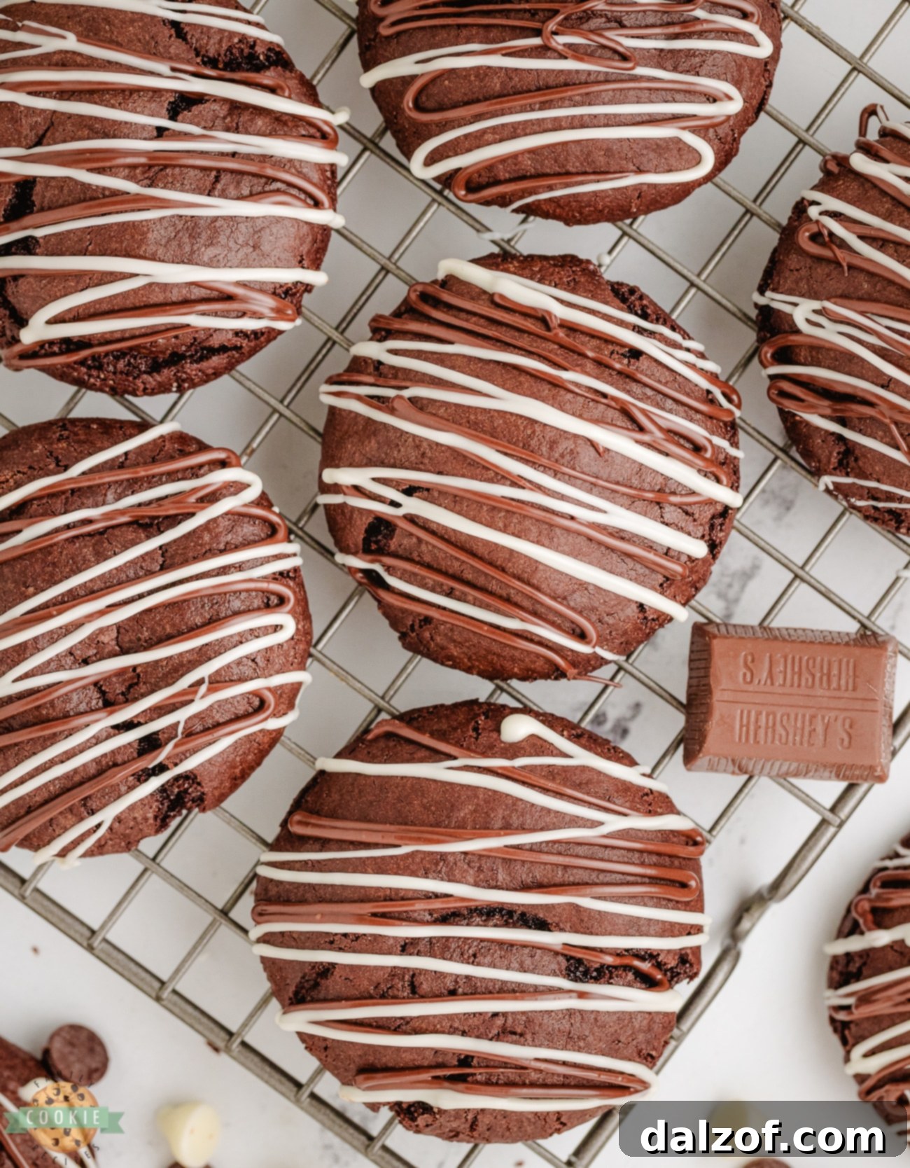 chocolate stuffed cake mix cookies on a cooling rack, some with melted chocolate drizzled on top