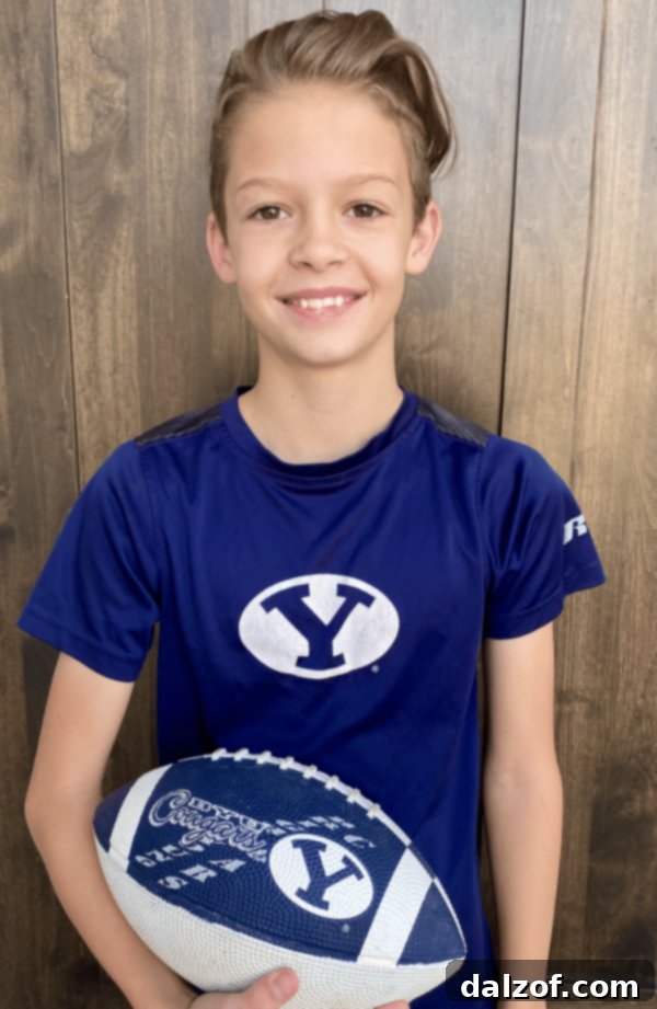 A young boy in a football uniform, likely the author's son, smiling.