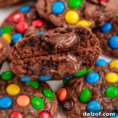 A brownie mix cookie broken in half, revealing its gooey chocolate interior and M&M candies.