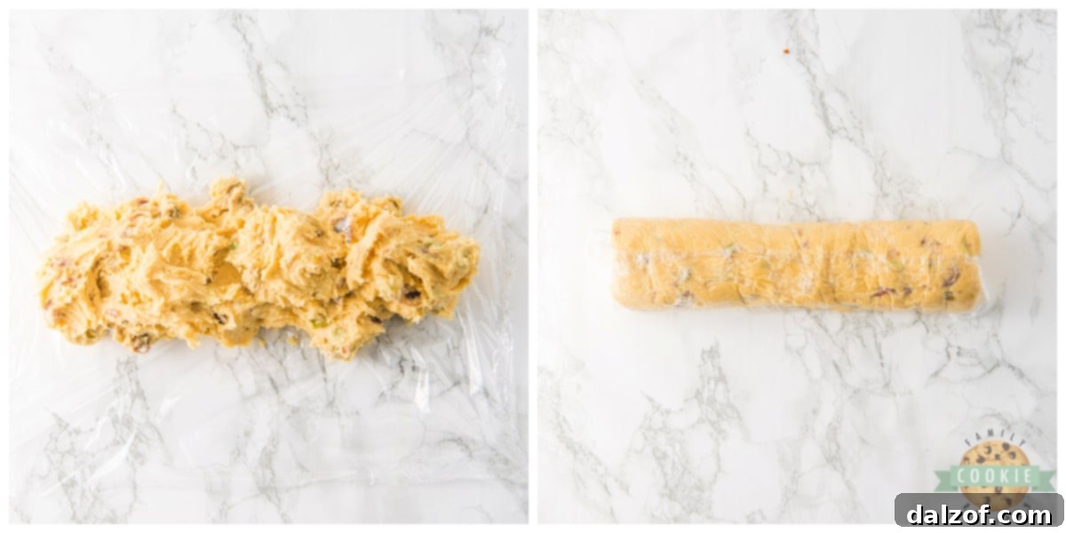 Cookie dough rolled into a cylindrical log and securely wrapped in plastic wrap, ready for freezing.