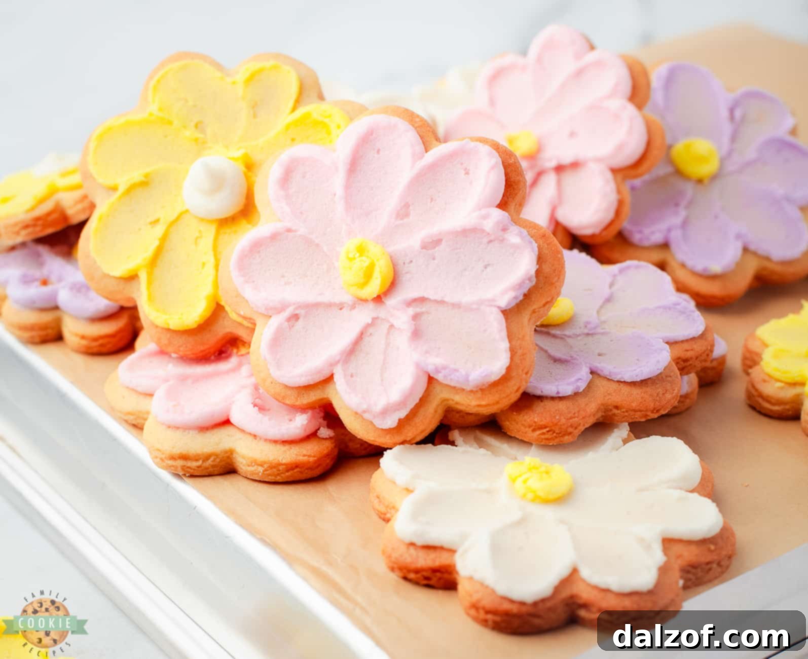 A charming pile of flower cookies adorned with intricately piped buttercream daisies in various pastel shades.