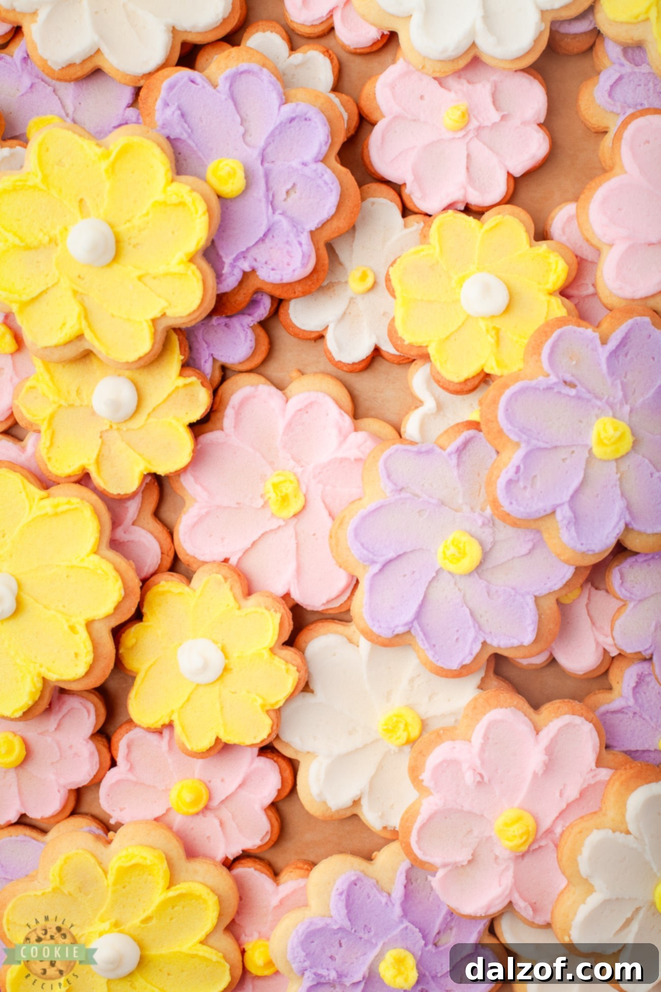 A vibrant assortment of yellow, pink, and lavender buttercream flower cookies, showcasing beautiful piping details.