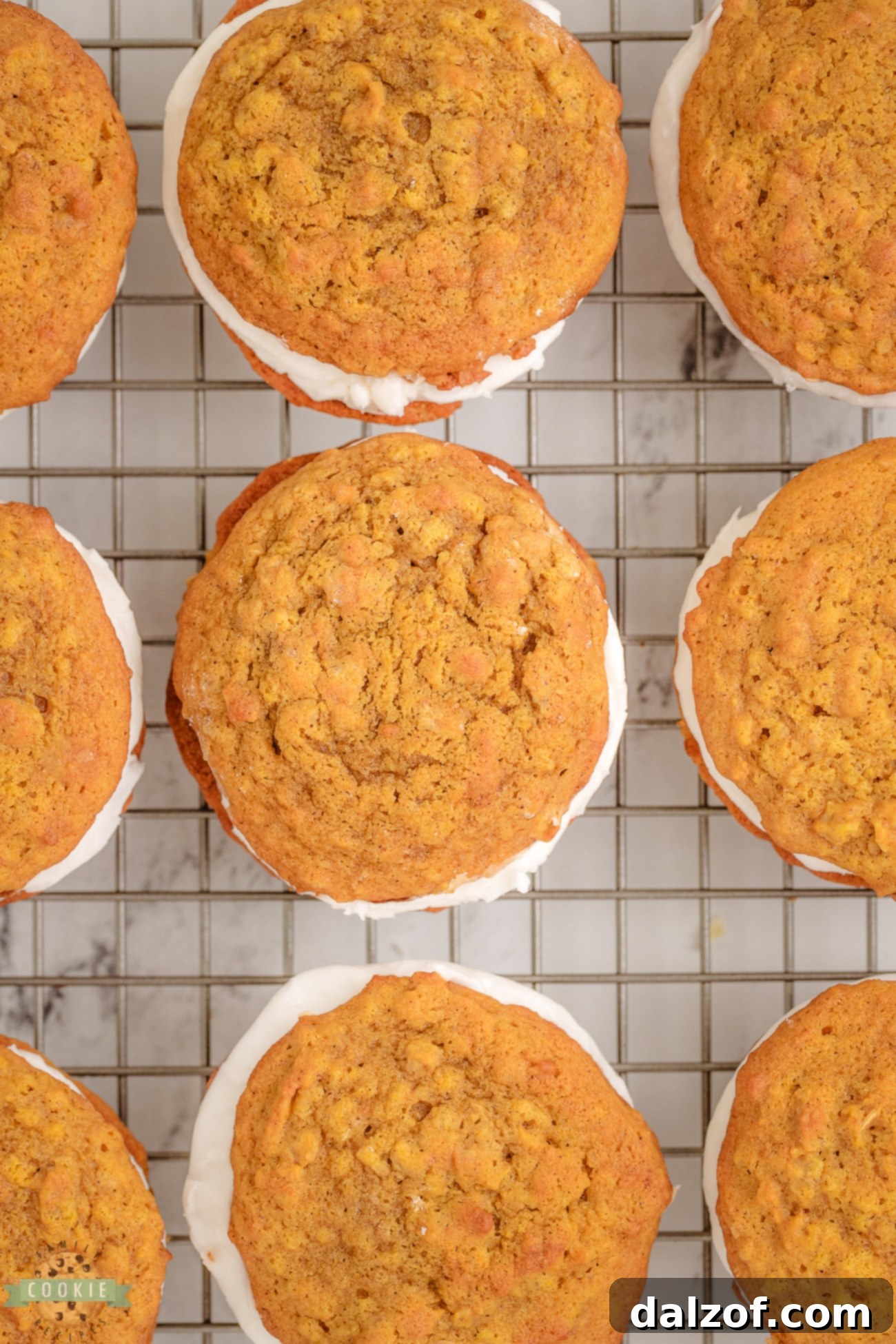 A plate of finished oatmeal pumpkin sandwich cookies, showcasing their golden color and thick maple frosting.