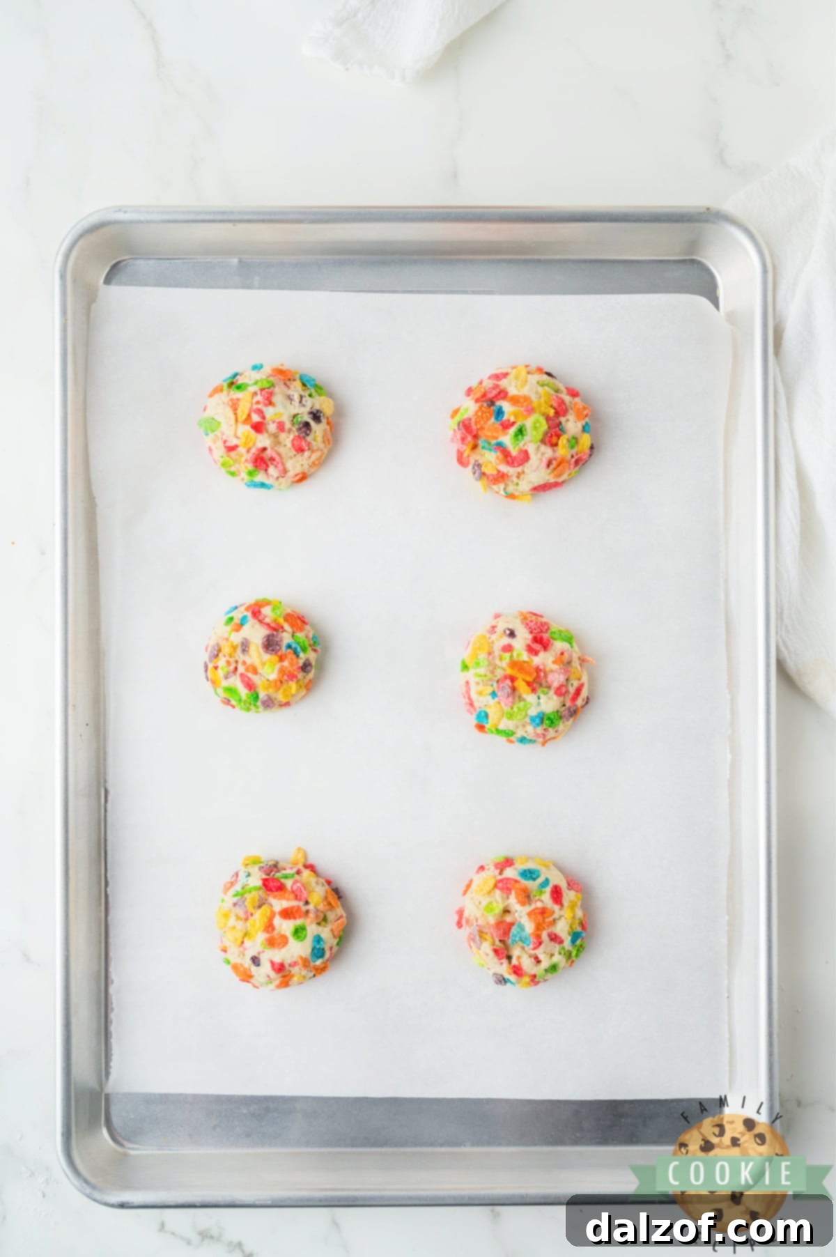 Fruity Pebbles cookie dough balls arranged on a baking sheet, ready for the oven.
