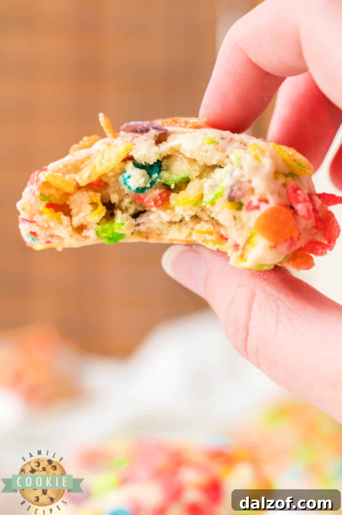 A Fruity Pebbles cookie with a bite taken out, showing the cereal pieces inside.