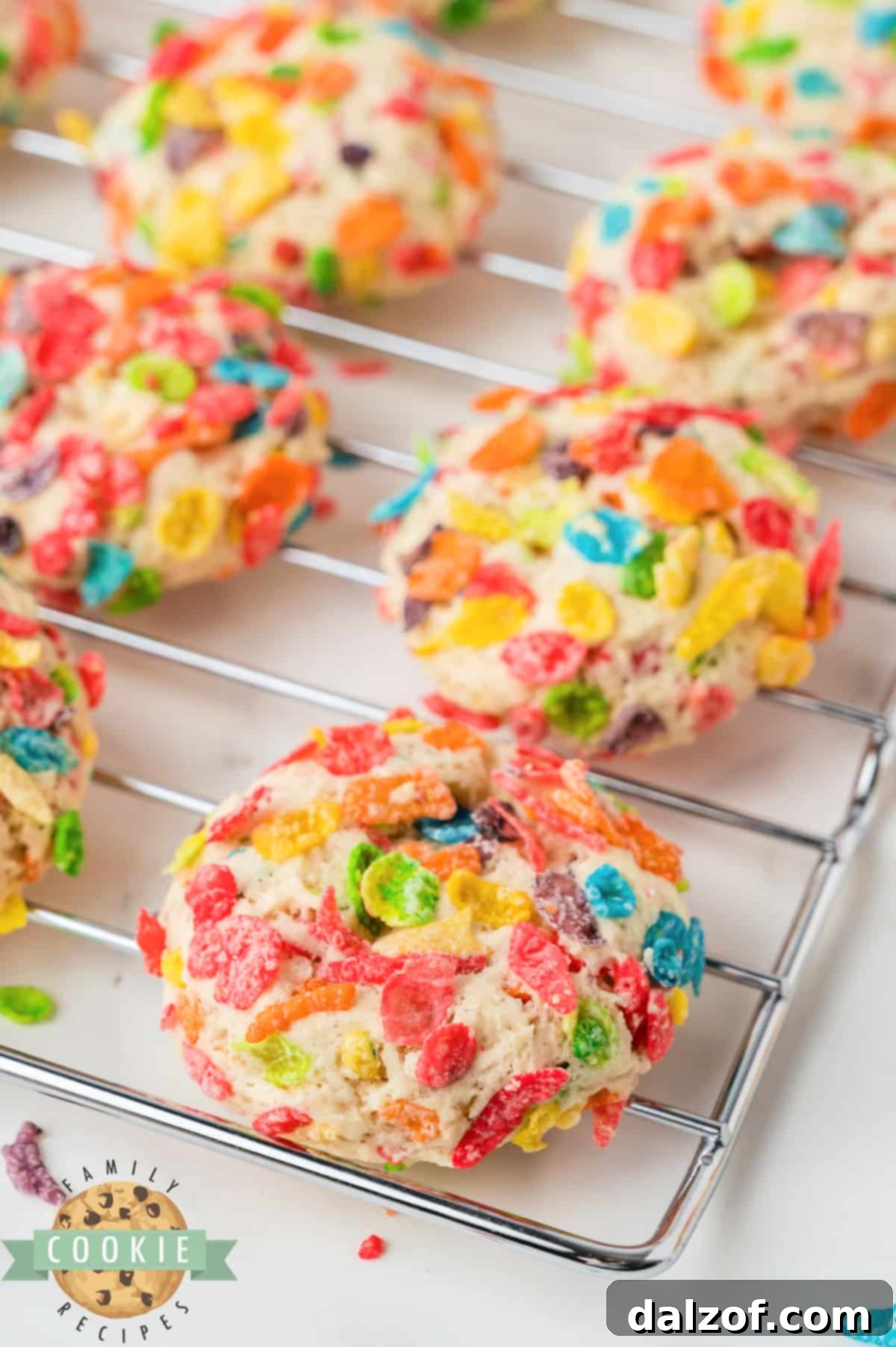 Close-up of cookie dough balls coated in Fruity Pebbles cereal, ready for baking.