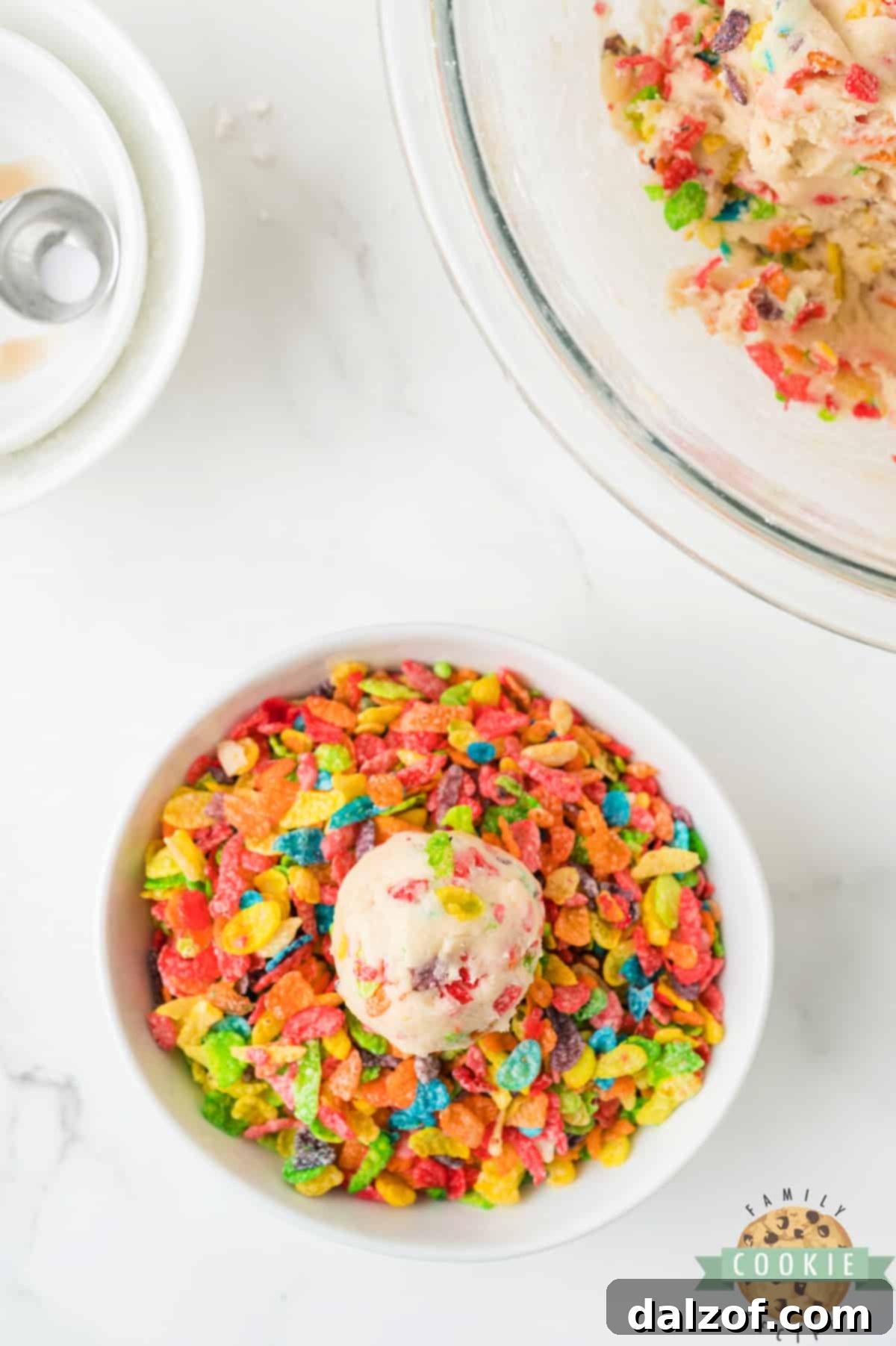 Rolling a ball of cookie dough in Fruity Pebbles cereal.