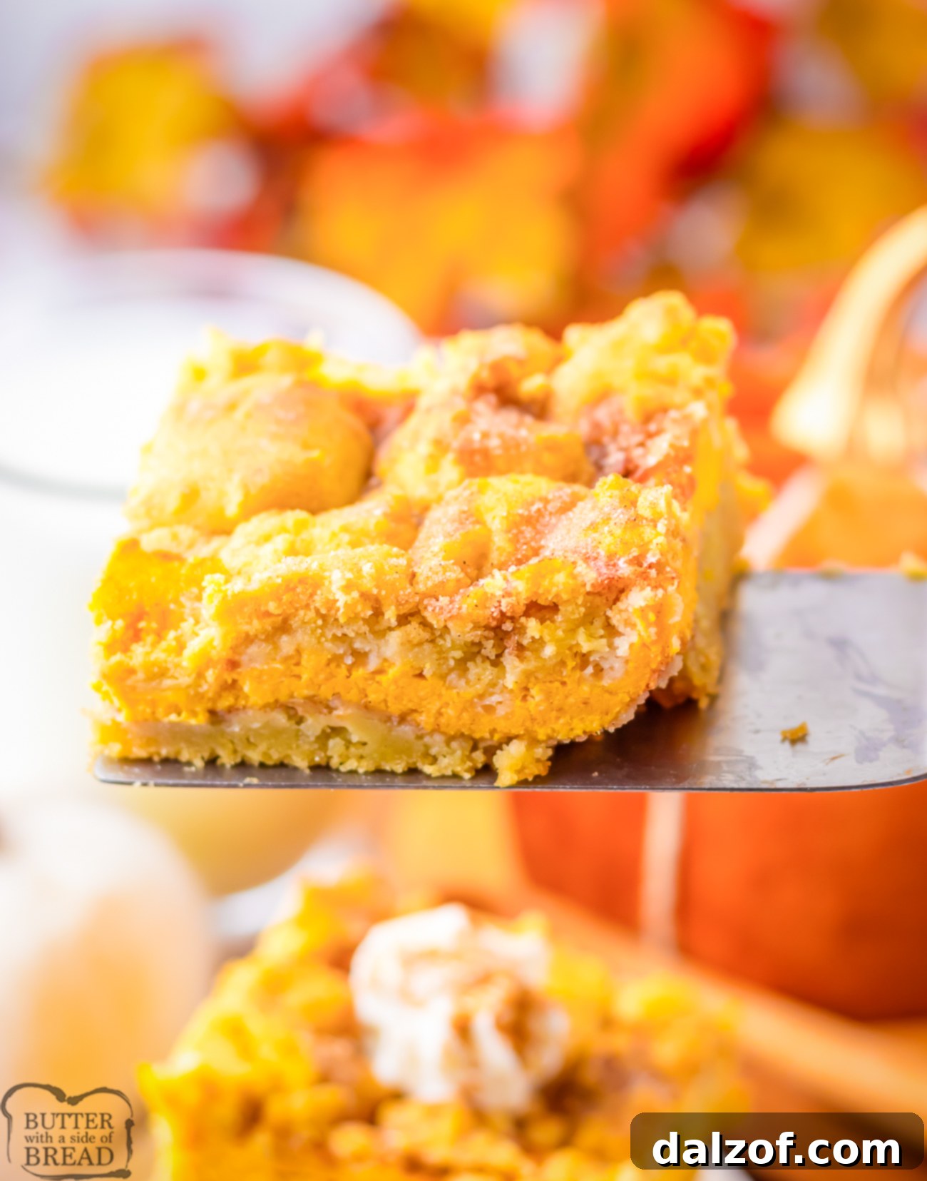 A hand holding a perfectly sliced Pumpkin Cheesecake Snickerdoodle Bar, showing the distinct layers of cookie, creamy pumpkin cheesecake, and cinnamon sugar topping.