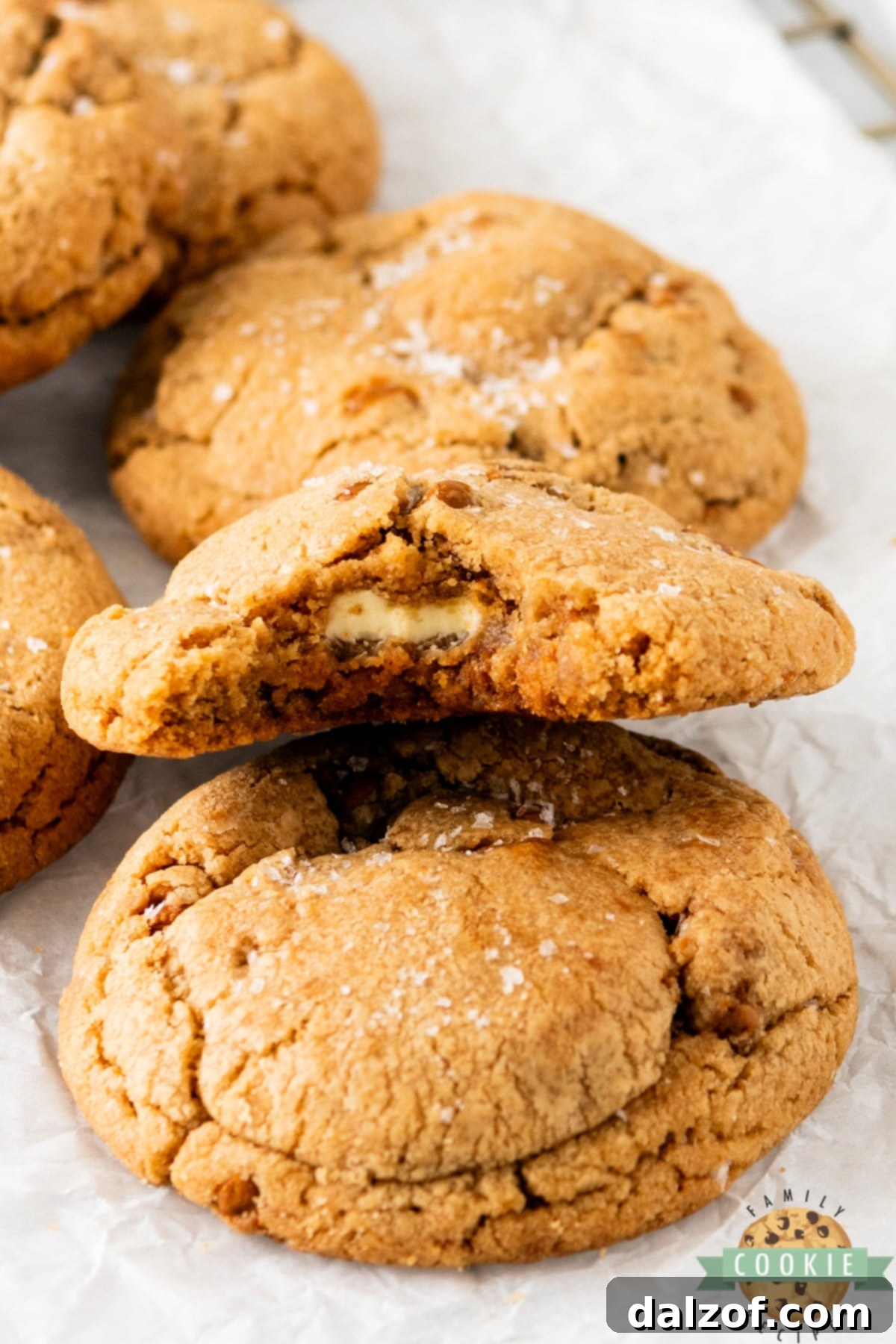 A warm Biscoff Butter Cookie broken in half to reveal the gooey melted white chocolate center.