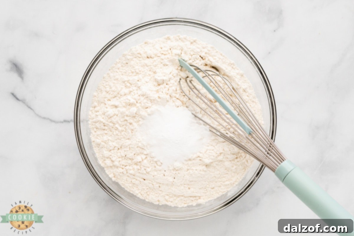Dry ingredients for cookies: flour, baking soda, and salt mixed in a bowl.
