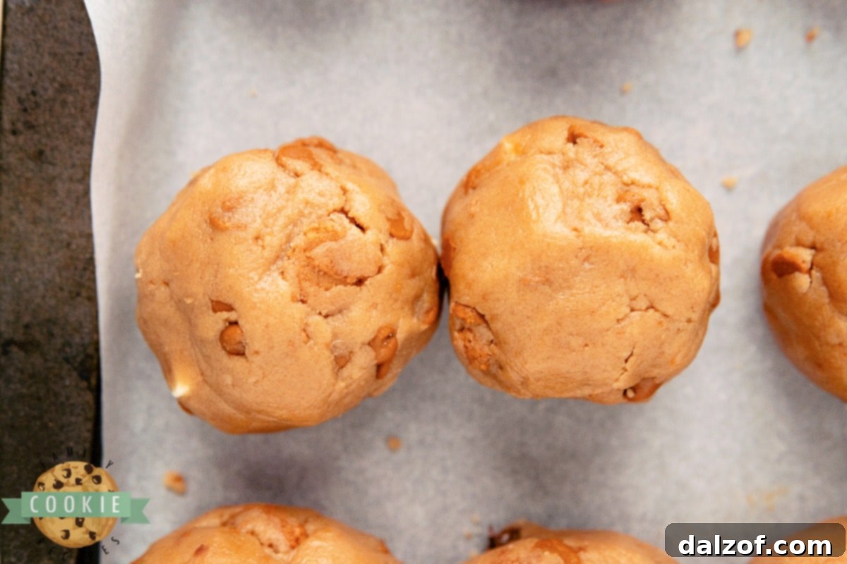 Uniformly shaped cookie dough balls with white chocolate centers, ready for chilling.
