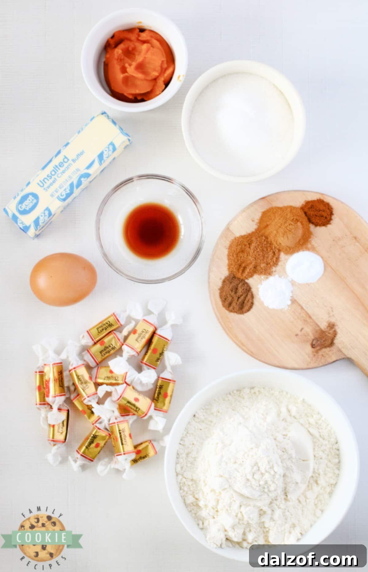 A visual display of all the essential ingredients laid out for Caramel Stuffed Pumpkin Snickerdoodles, including flour, spices, butter, egg, vanilla, pumpkin puree, sugar, and soft caramels.