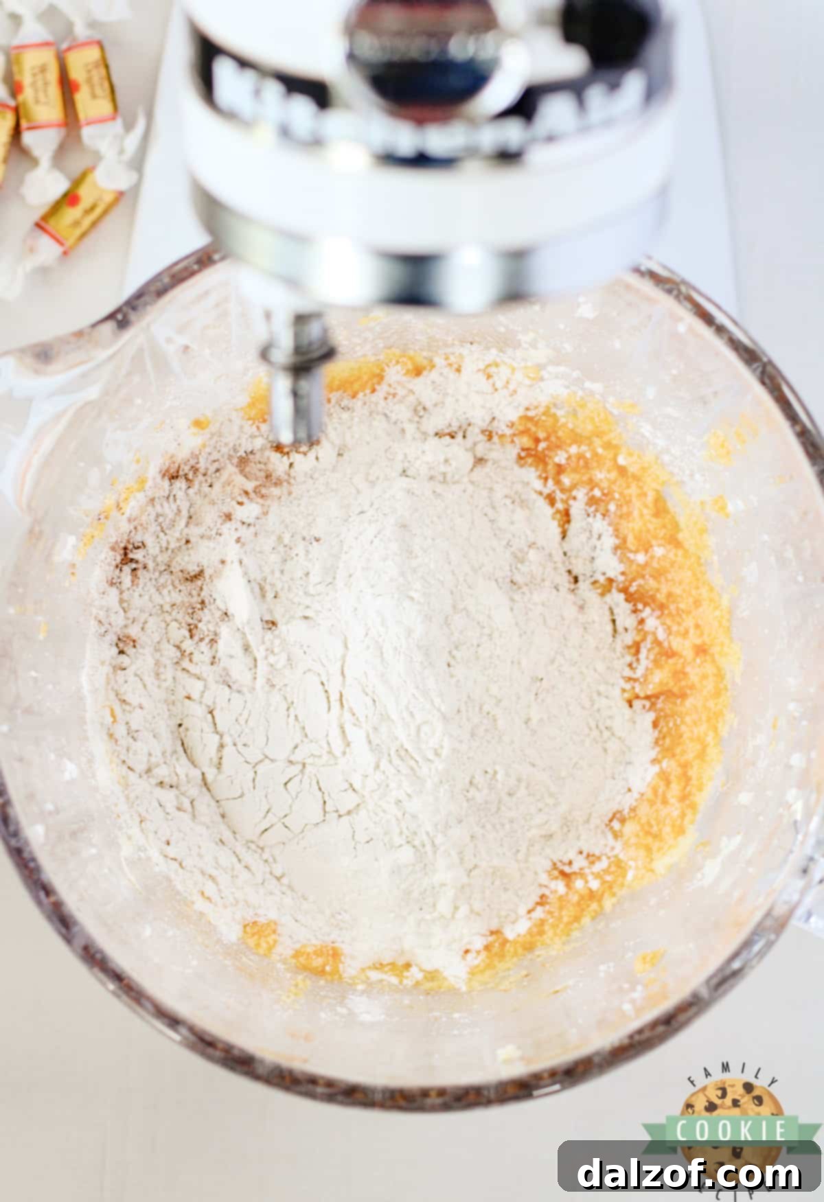 The mixing bowl with wet ingredients now combined with the dry flour and spice mixture, being gently blended together to form a soft, cohesive cookie dough.