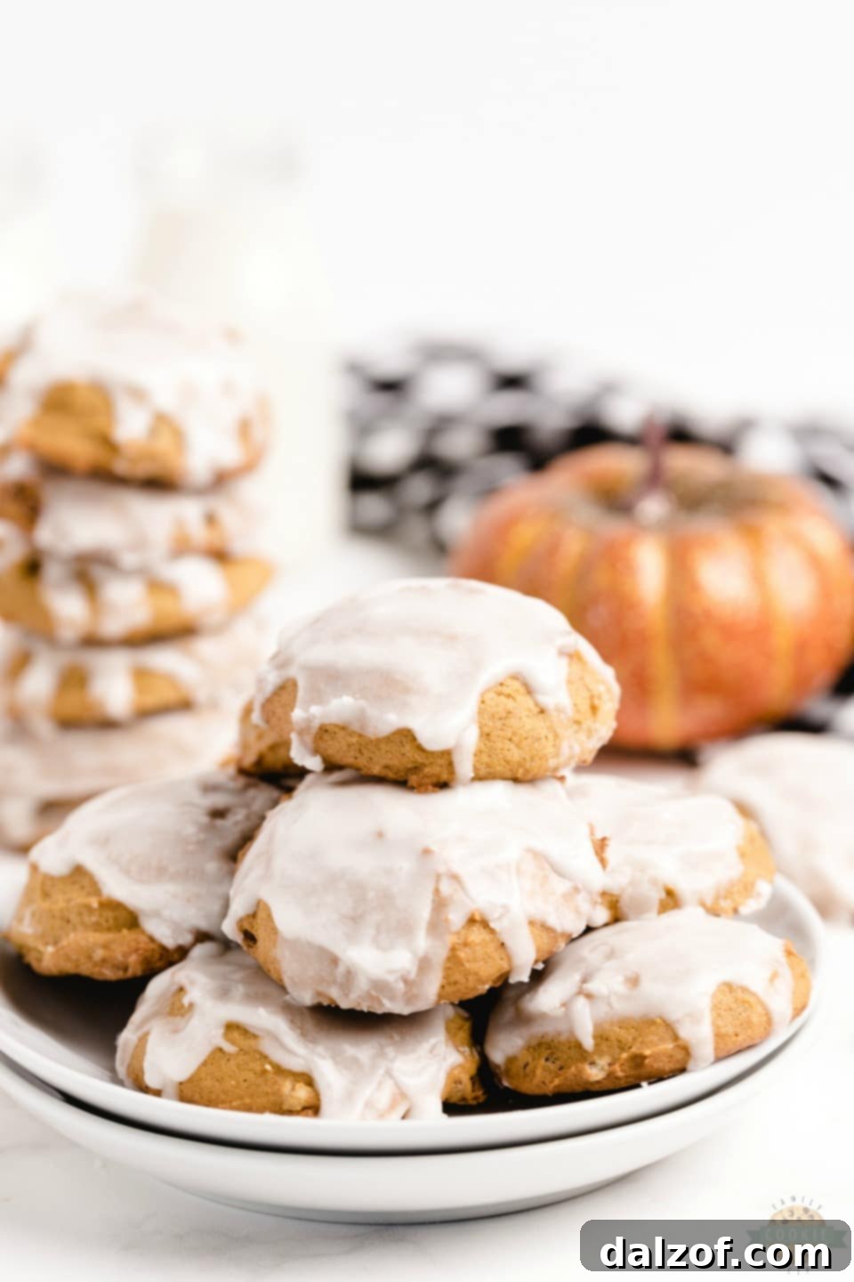 Close-up of a stack of pillowy soft iced pumpkin cookies with vanilla glaze, showcasing their tender texture