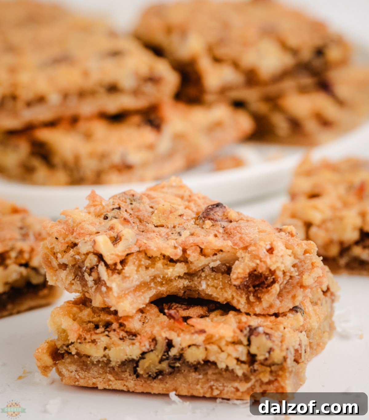 Close-up of a Coconut Dream Bar with a bite taken out, showing the rich, chewy coconut filling and crunchy walnuts on top of a buttery crust.