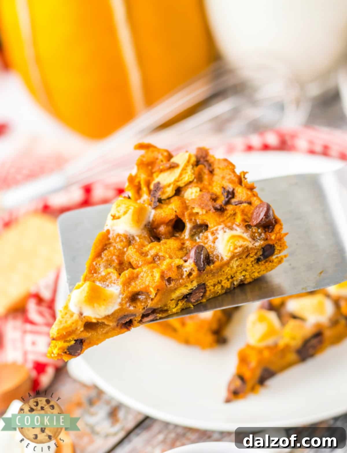 Ooey Gooey Pumpkin S'mores Cookie Cake 14 A top-down view of a round Pumpkin cookie pizza, adorned with toasted marshmallows and chocolate, cut into slices, perfect for a festive fall gathering.