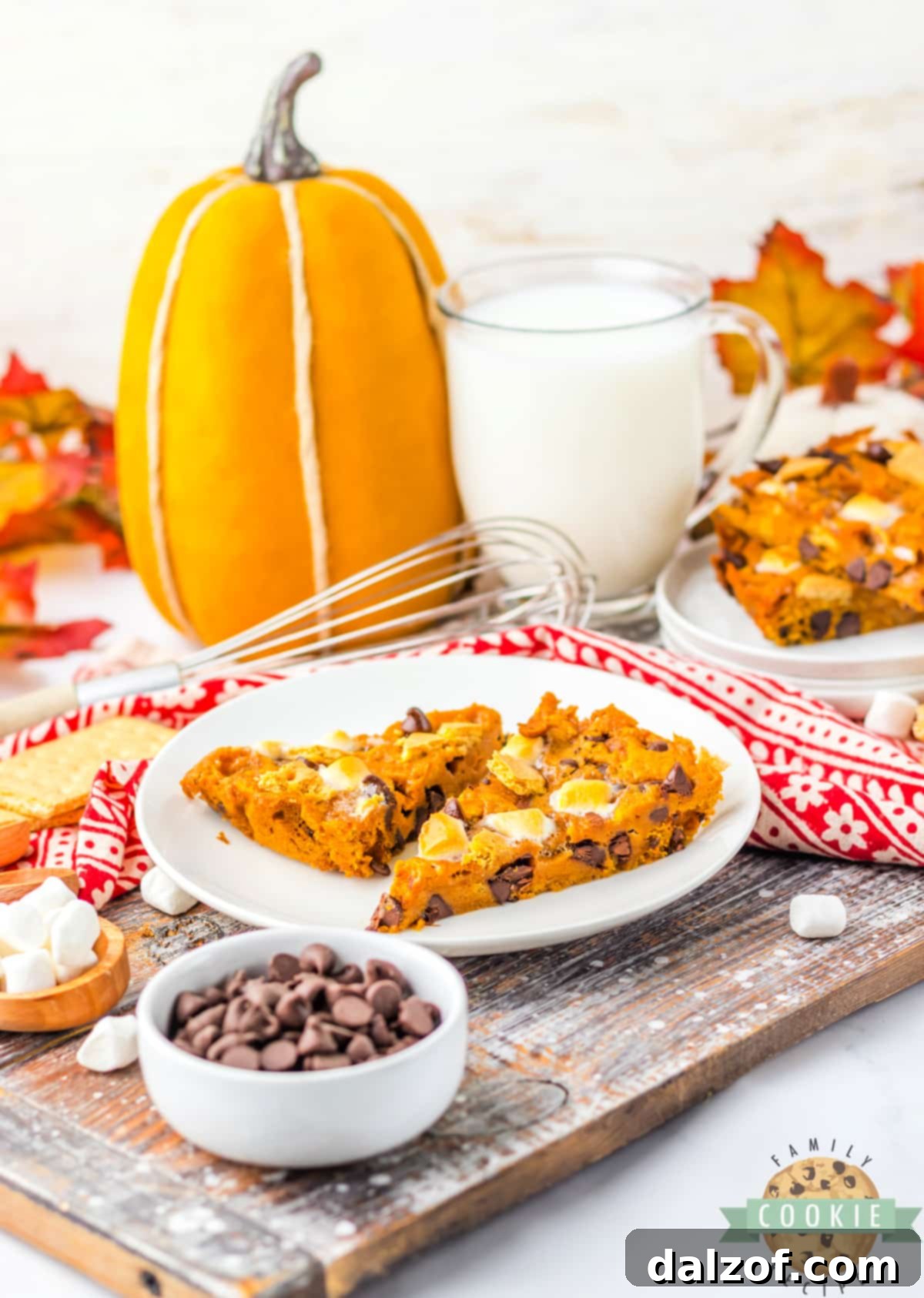 Ooey Gooey Pumpkin S'mores Cookie Cake 16 An autumn-themed dessert spread featuring a delicious Pumpkin S’mores Cookie Cake, surrounded by fall decorations like miniature pumpkins and leaves.