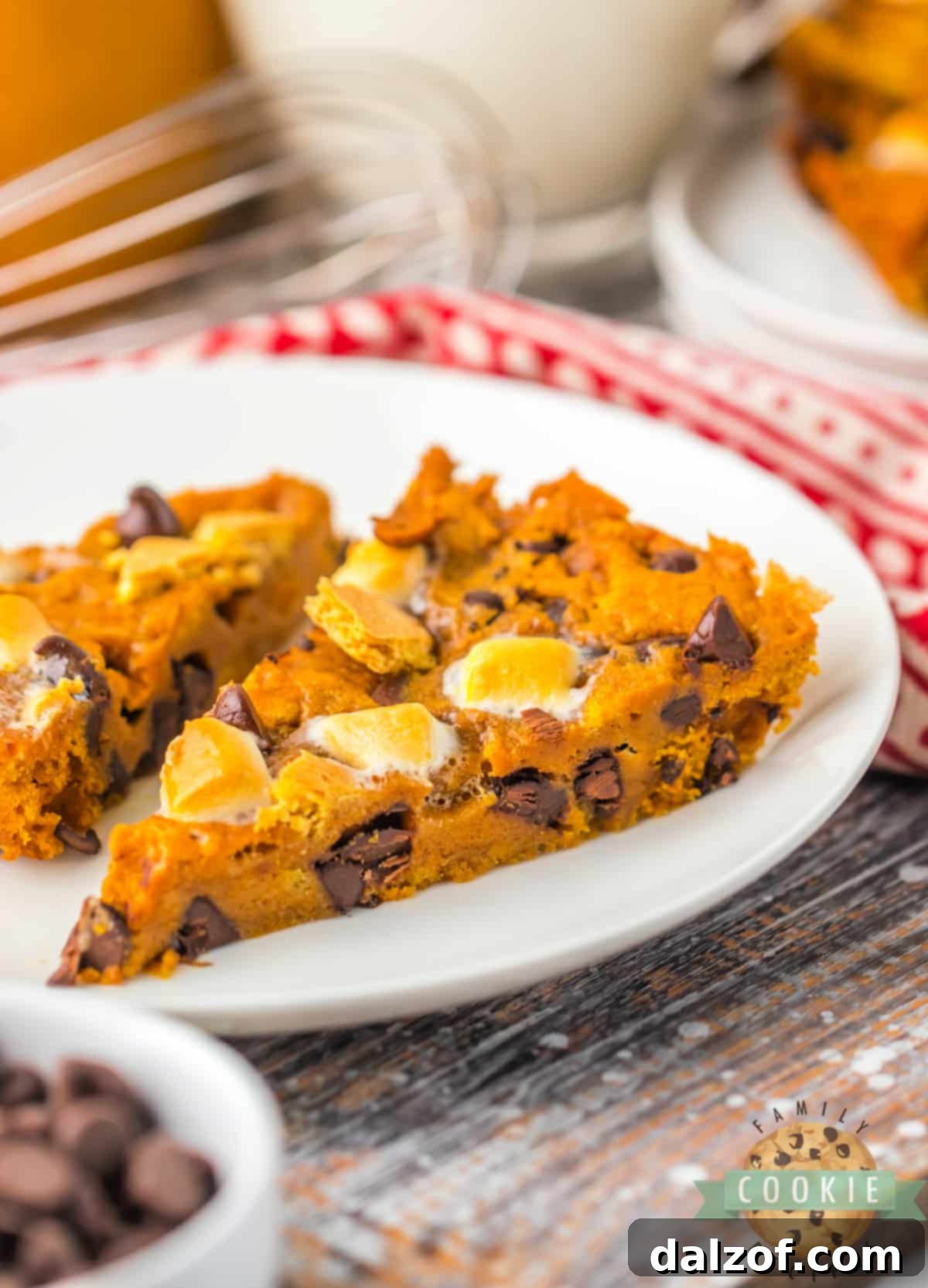 Ooey Gooey Pumpkin S'mores Cookie Cake 5 A perfectly baked slice of Pumpkin S’mores Cookie Cake, featuring visible layers of melted chocolate, toasted marshmallows, and graham cracker crumbs, resting on a serving plate.