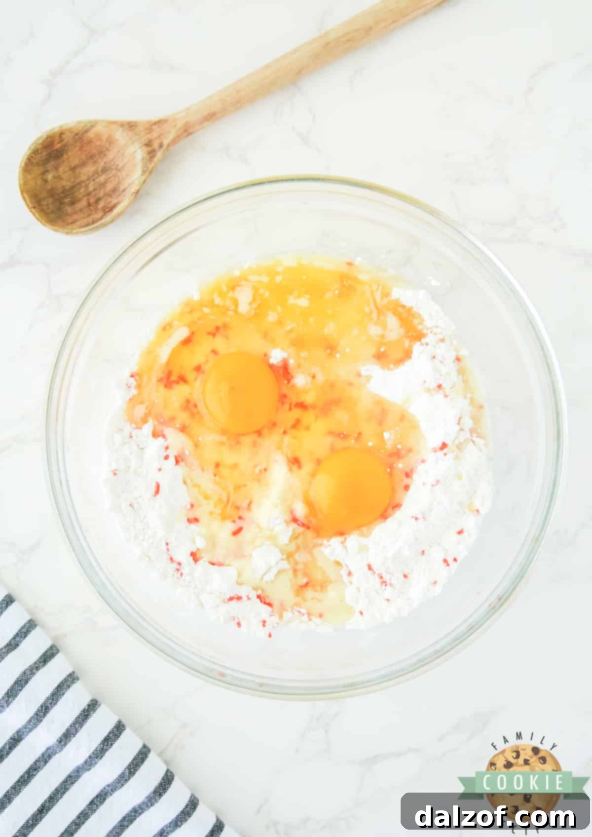 Oil, melted butter, and eggs being added to the cake mix and sprinkle mixture in a mixing bowl.