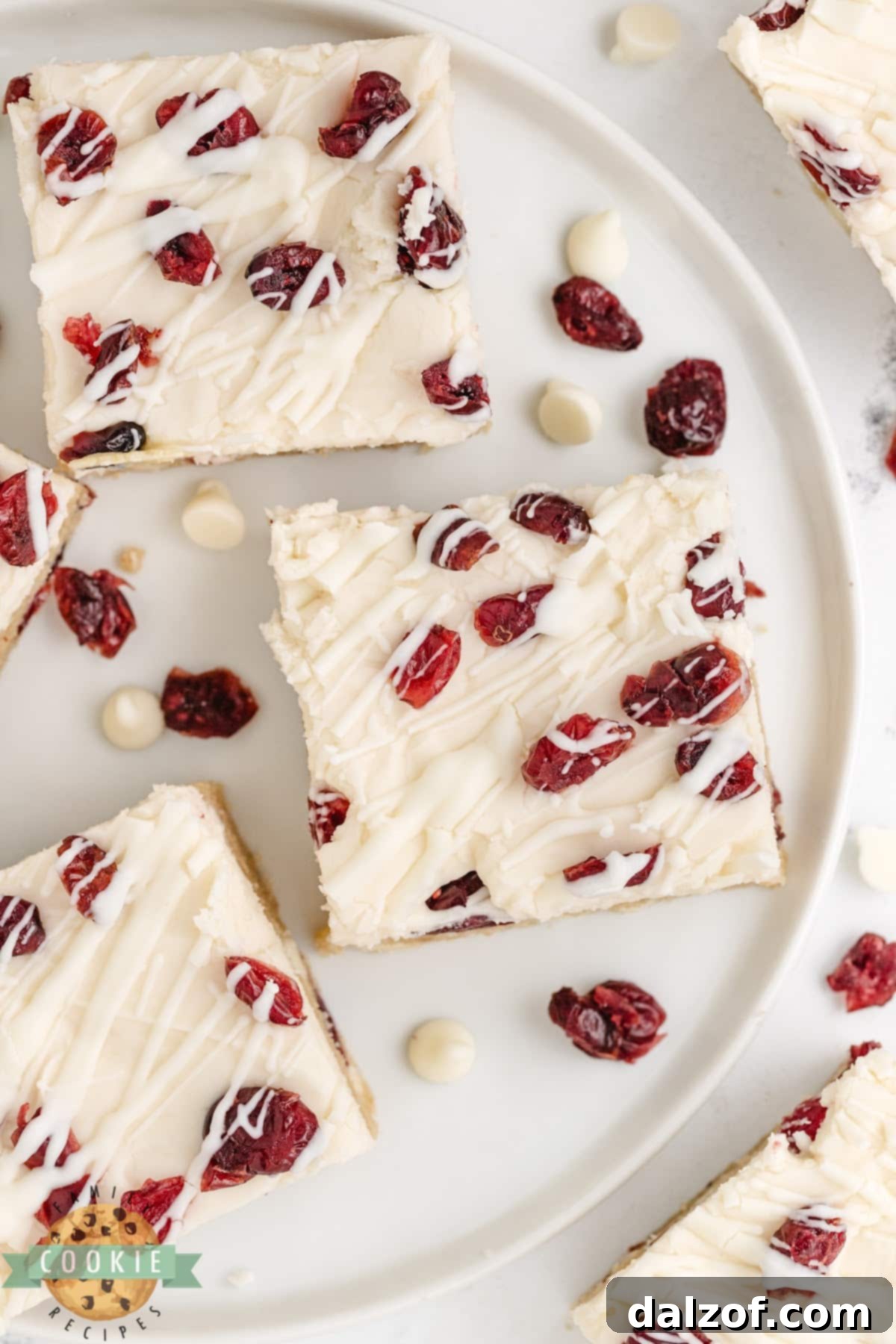 Cookie bars topped with cream cheese frosting, Craisins, and white chocolate drizzle. 
