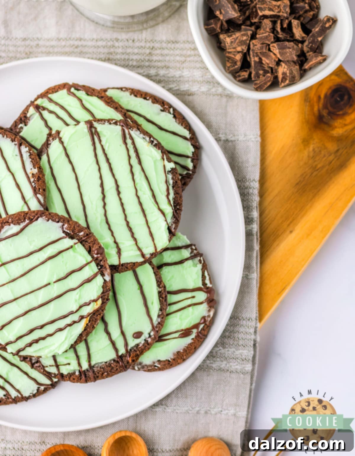 A close-up view of chocolate cookies with smooth green mint frosting, ready for the chocolate drizzle or serving.