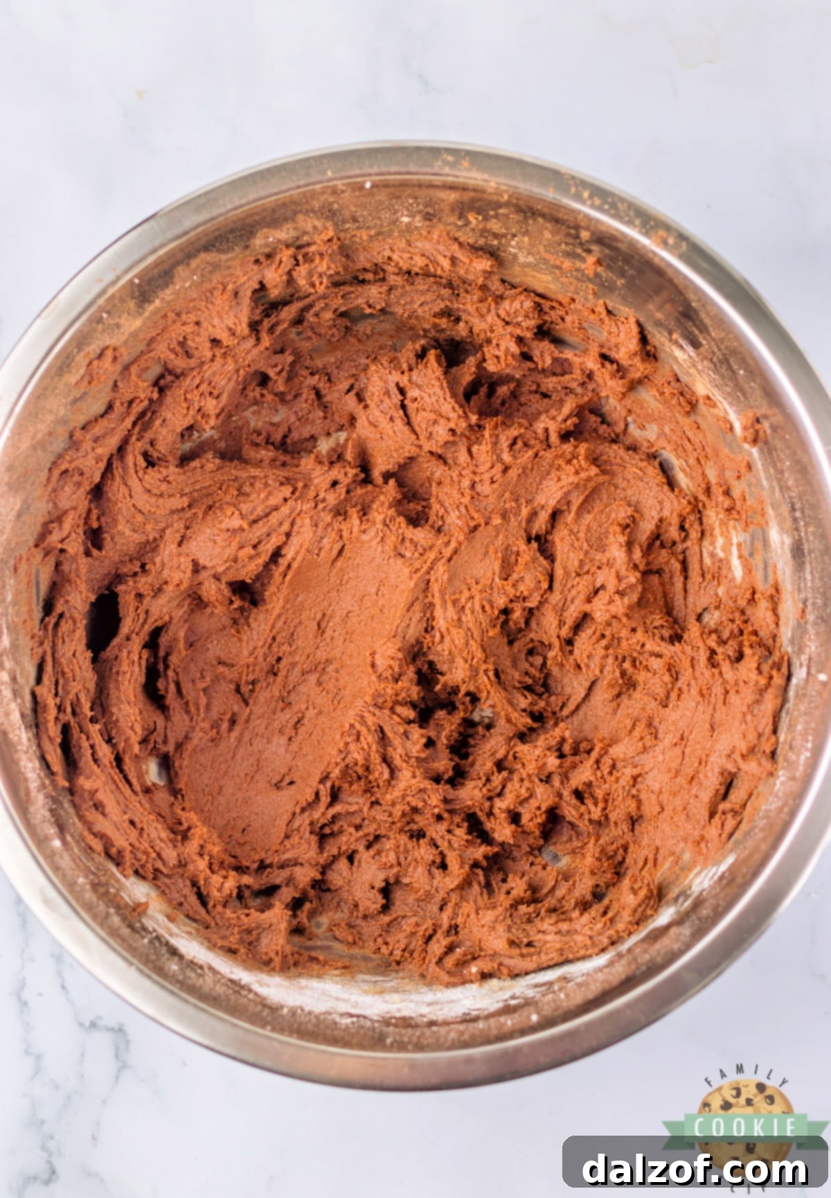 A close-up of rich, dark chocolate cookie dough in a mixing bowl, showing its smooth and uniform texture after all ingredients are combined.