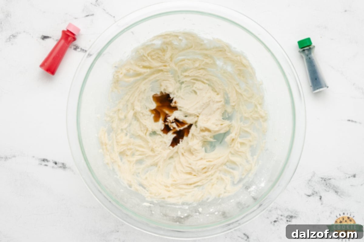 Vanilla extract being drizzled into fluffy buttercream frosting, enhancing its flavor.