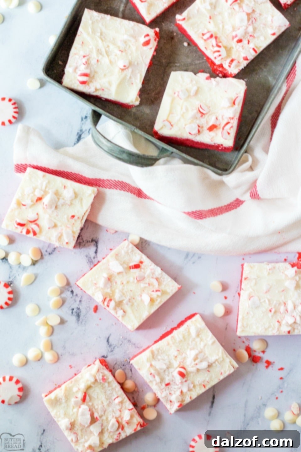 Close-up of a festive Frosted Peppermint Cookie Bar, featuring a red sugar cookie base, white chocolate frosting, and crushed peppermint candies. Perfect for holiday baking and Christmas treats.