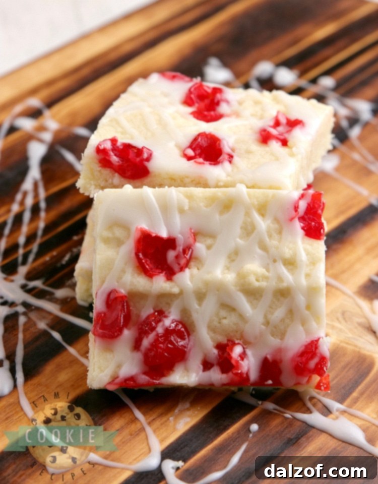 A beautifully arranged plate of glazed sugar cookie bars with cherries, garnished and ready to be enjoyed.